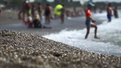 Boy wearing inflatable armbands, kid from pebble beach goes into sea waves Video stock 335763593