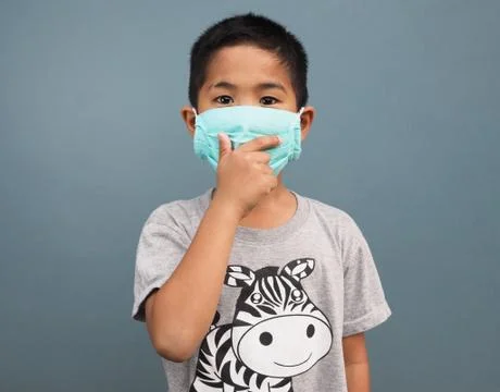 A boy wearing a protective mask While covering his hand while coughing. Stock Photos