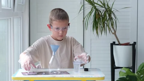Boy wearing safety glasses performs a chemical experiment Stock Footage 328506227