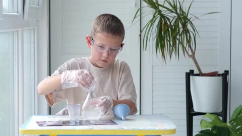 Boy wearing safety glasses performs a chemical experiment Stock Footage 328506295