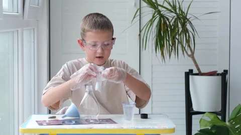 Boy wearing safety glasses performs a chemical experiment. Stock Footage 328506847