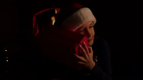 A boy wearing a Santa hat shakes and opens a gift box on Christmas Stock Footage 166643898