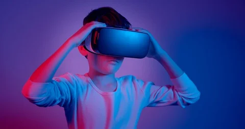 Boy wearing VR glasses looking around under neon lights. Stock Footage 128397677