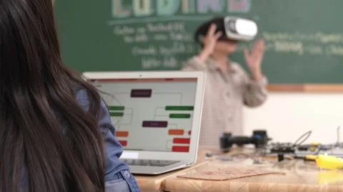 Boy wearing VR headset to enter metaworld while girl coding system. Pedagogy. Stock Footage 273833605