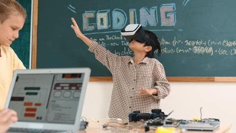Boy wearing VR headset to enter metaworld while girl coding system. Pedagogy. Stock Photos