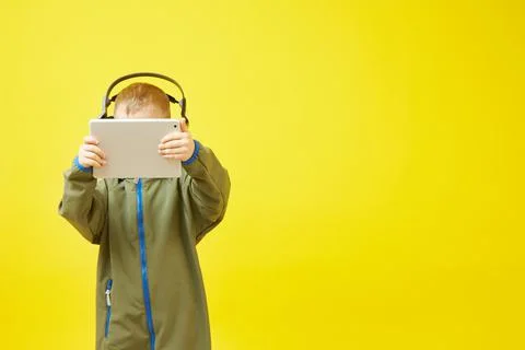 Boy wears headphones while using tablet computer Stock Photos