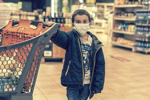 Boy wears protected mask in store. Shopping time during coronavirus outbreak Stock Photos