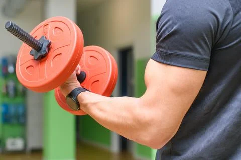 Boy while working out in gym with dumbbell weights Stock Photos