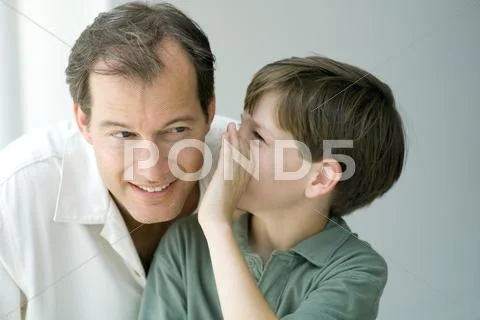 Boy whispering in father's ear, close-up Stock Photos