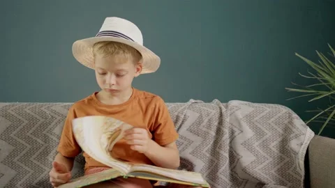 Boy in white hat reads a book at home. child homeschooling Stock Footage 158856864