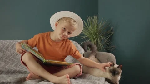 Boy in a white hat stroking a cat at home. children and pet Stock Footage 158855430