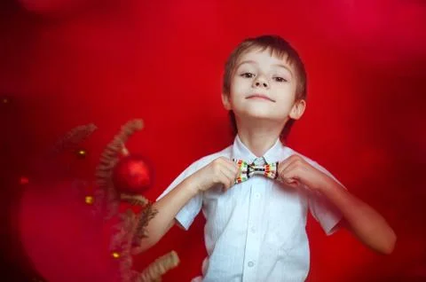 Boy in white shirt correcting a bow tie dressed up in Christmas tree Stock Photos