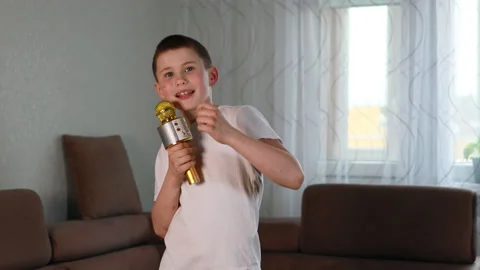 Boy in white shirt singing using microphone at home Stock Footage 153584059