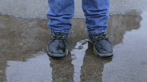 A boy in winter boots jumping in a puddle Stock Footage 84085817