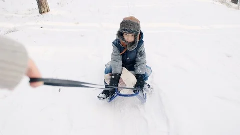 Boy in winter hat sledding Stockbeeldmateriaal 99397951