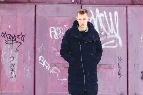 Boy in a winter jacket against the background of the wall Stock Photos