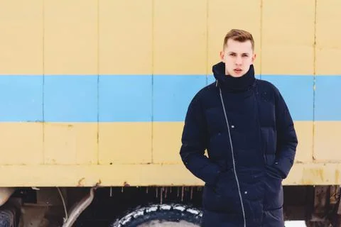 Boy in a winter jacket against the background of the wall Stock Photos