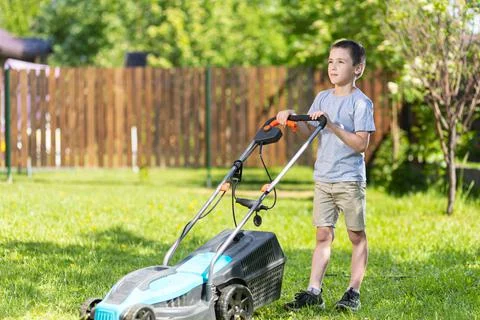 Boy worker on the garden working on mowing the lawn with the help of a modern Stock Photos