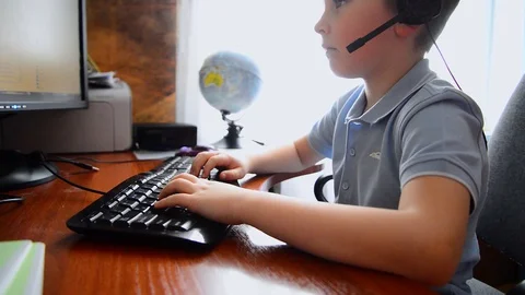 The boy is working at a computer on the table at home,distance learning Stock Footage 128310834