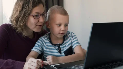 Boy working on a computer together with his mom at home. E-lessons, education Vídeos de archivo 120285125