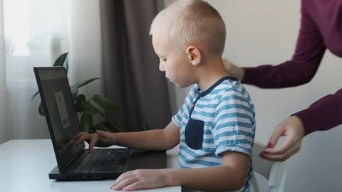 Boy working on a computer together with his mom at home. E-lessons, education Stock Footage 120285140