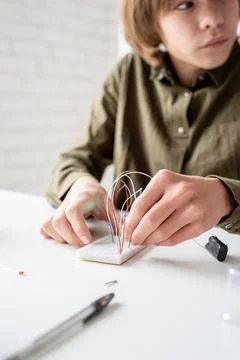 Boy working with LED lights on experimental board for science project Stock Photos