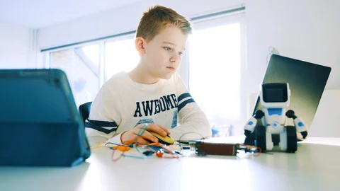 Boy works with electronics connected to laptop and looks at the screen Stock Footage 102173005