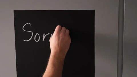 Boy writes on a chalk board with chalk the phrase sorry I am gay Stock Footage 168816388