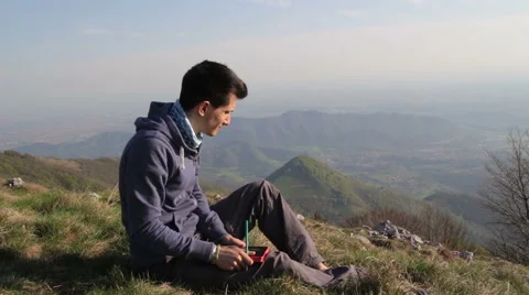Boy writes in his diary, on top of the mountain Stock Footage 50719936