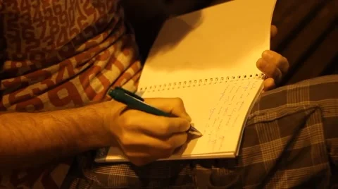 BOY WRITES LETTER IN THE NOTEBOOK ON THE BENCH AT NIGHT Video stock 65293320
