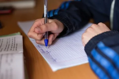 The boy writes in a notebook. The child is doing homework. Pen and notebook. Stock Photos