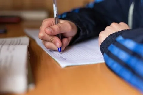 The boy writes in a notebook. The child is doing homework. Pen and notebook. Stock Photos