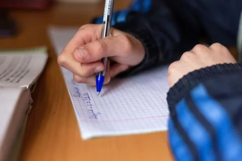 The boy writes in a notebook. The child is doing homework. Pen and notebook. Stock Photos