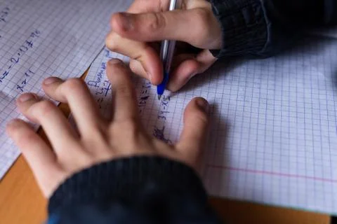 The boy writes in a notebook. The child is doing homework. Pen and notebook. Stock Photos