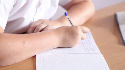 Boy writes in a notebook sitting at a desk. hands closeup Video stock 64746613