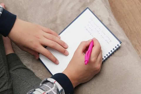 The boy writes with a pen in the notebook. Stock Photos