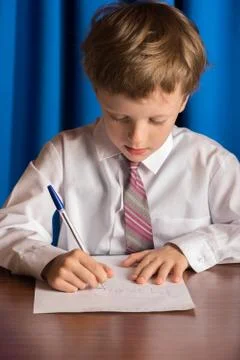 Boy writes on a sheet of paper Stock Photos