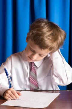 Boy writes on a sheet of paper Stock-Fotos