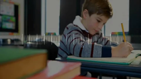 Boy writing in notebook at classroom desk, showing floating pencil icon and Stock Footage 330469971