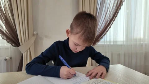 The boy is writing in a notebook with a pen - doing homework Stock Footage 299288621