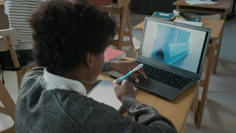 Boy Writing in Notebook, While Using his Laptop in Modern 3D Modelling Class Stock Footage 301911779