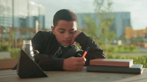 Boy Writing Thoughtfully On Wooden Table With Snack And Drink Stock Footage 318853103