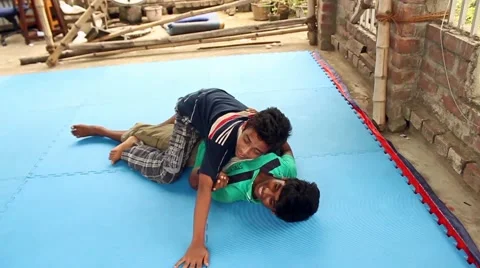 Boy yawns as another practices a take-down on him while practicing jiu jitsu Stock Footage 58459132