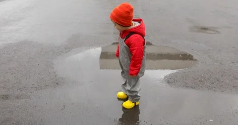 Boy in yellow boots walking through puddles Video stock 118764381