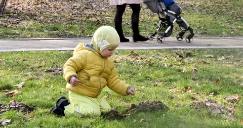 Boy yellow clothes is picking ground. Two year playing with soil in early spring Stock Footage 244747080