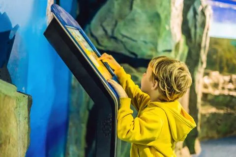 The boy in the yellow jacket uses a touch screen Stock Photos