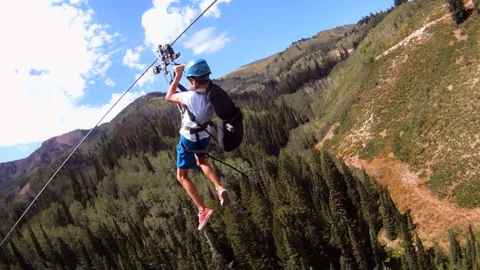 Boy zip lining over mountain valley, Canyons Village, Park City, Utah. Video stock 98013411