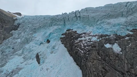 Boyabreen Glacier in clear daylight with ice and cliffs, aerial. Stock Footage 321005017