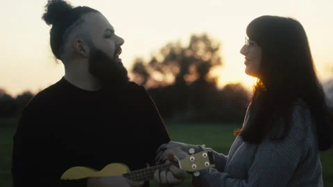 Boyfriend playing ukulele at sunset Stock Footage 232034704