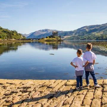 Boys (6-7) looking at Eileen Donan Castle Stock Photos